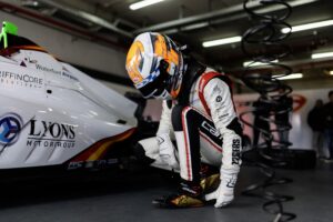 Piloto agachado junto a su monoplaza en el box antes de salir a pista
